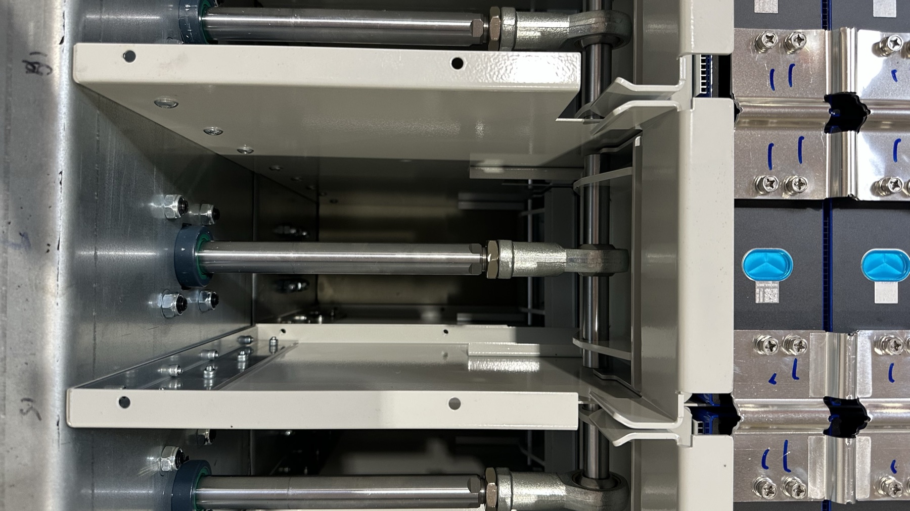Pneumatic compression cylinders pressing on the end plates of the cell rows, with cells and busbars to the right.