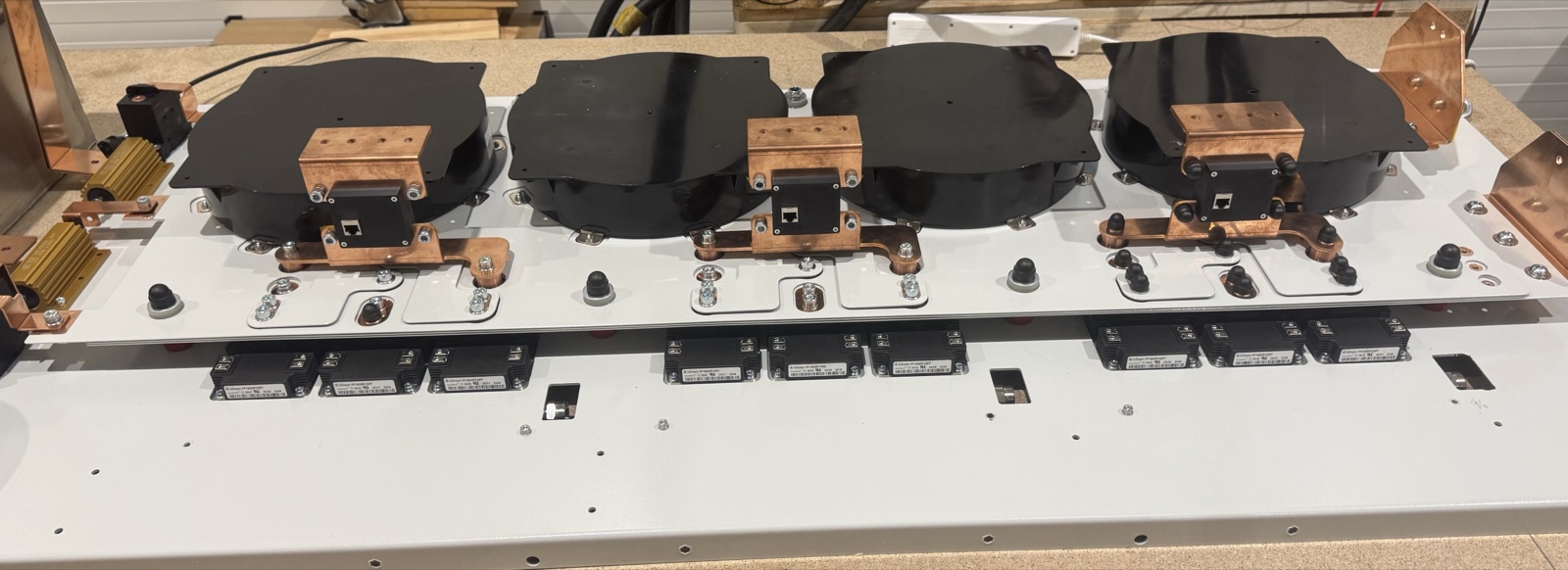 The underside of a Bessify PCS base panel during build, showing four potted magnetics, copper busbars and rows of power modules.